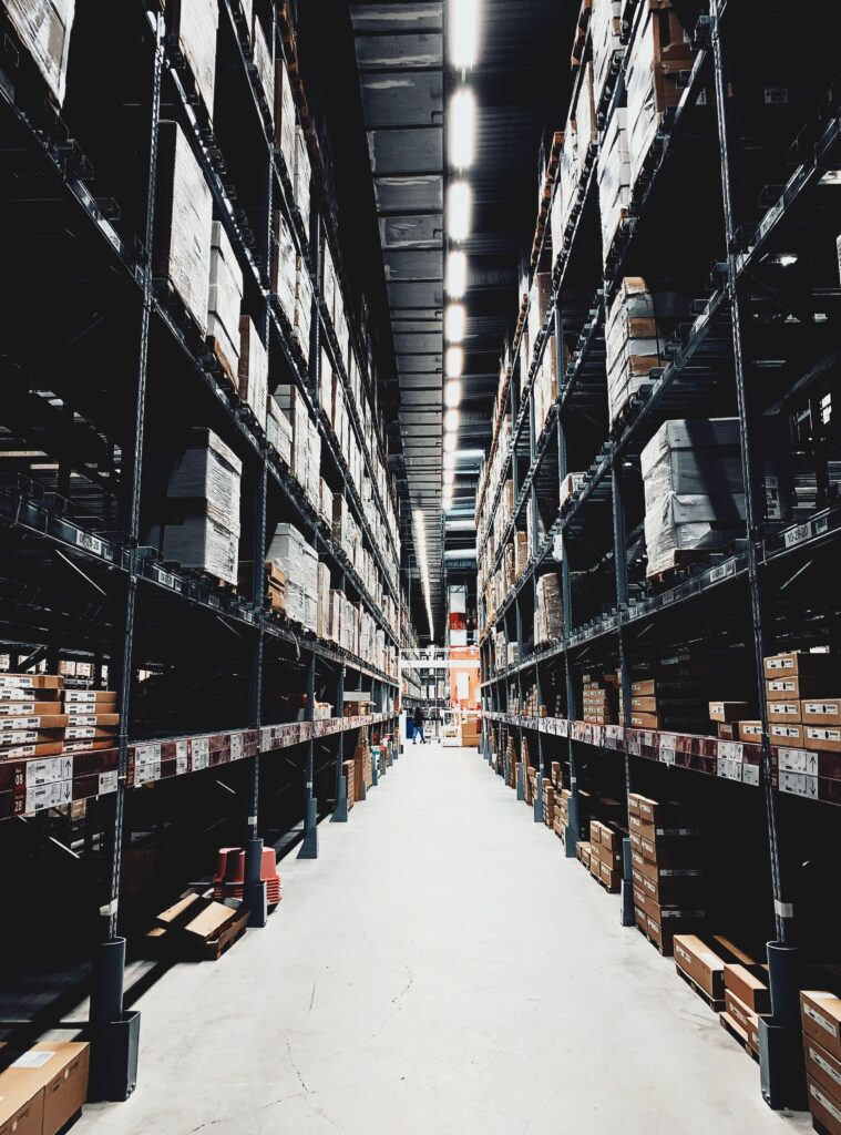 oil-1 A wide aisle in a large warehouse filled with stacked boxes on high shelves.